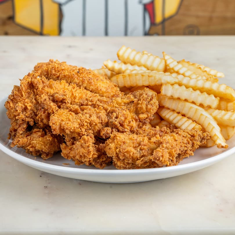 Crispy fried chicken tenders and crinkle-cut fries on a white plate.